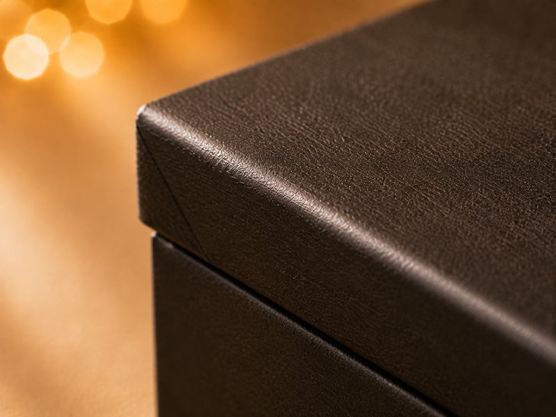 Macro view of a wrapped box corner showing specialty paper folded cleanly over the board edge